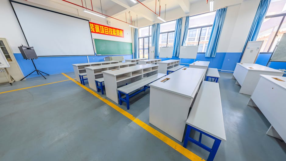 A spacious modern classroom with blue and white decor, featuring desks and a projector screen
