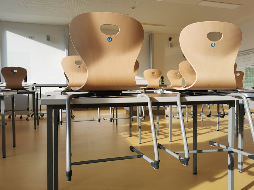 Bright and tidy empty classroom with wooden chairs and tables ready for students